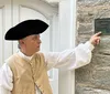 A woman in historical costume is speaking to two attentive listeners on a sidewalk possibly conducting a historical tour