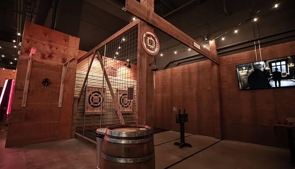 The image shows an indoor axe throwing range with wooden targets safety netting and a rustic aesthetic