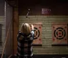 A person is throwing an axe toward a target at an indoor axe-throwing facility
