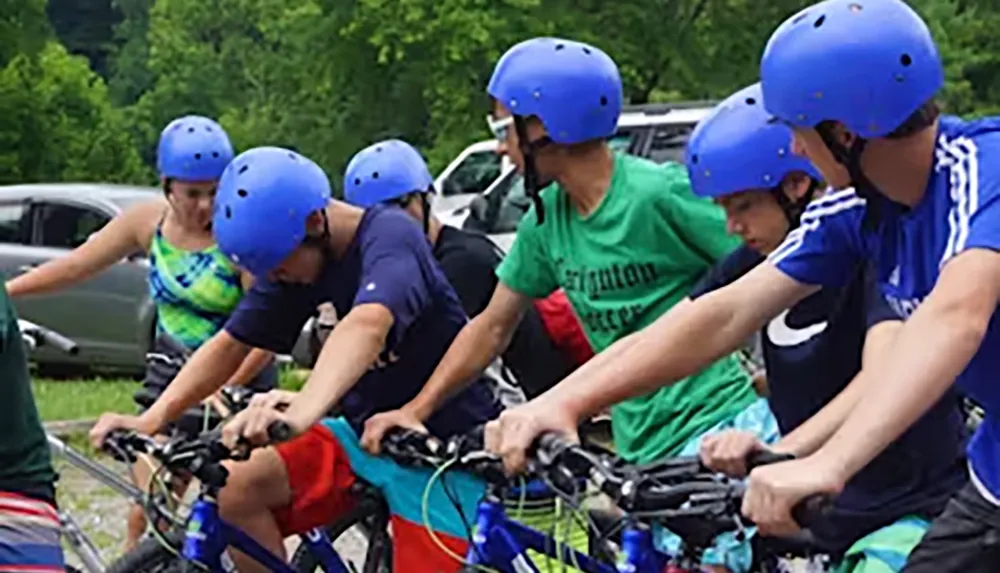 A group of individuals wearing blue helmets is engaged in a tandem bike ride outdoors