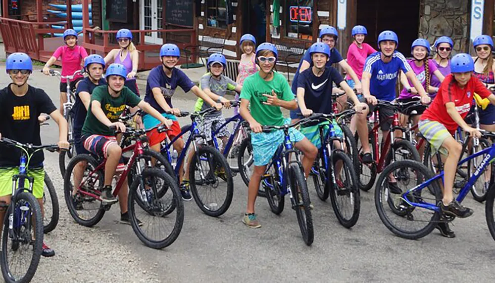 A group of smiling young people in helmets are poised on mountain bikes seemingly ready for a group ride