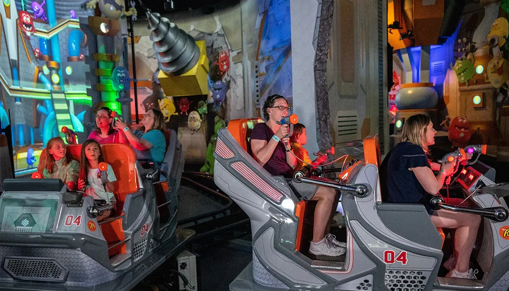 The image shows people on a ride using blasters to interact with a colorful game-like environment
