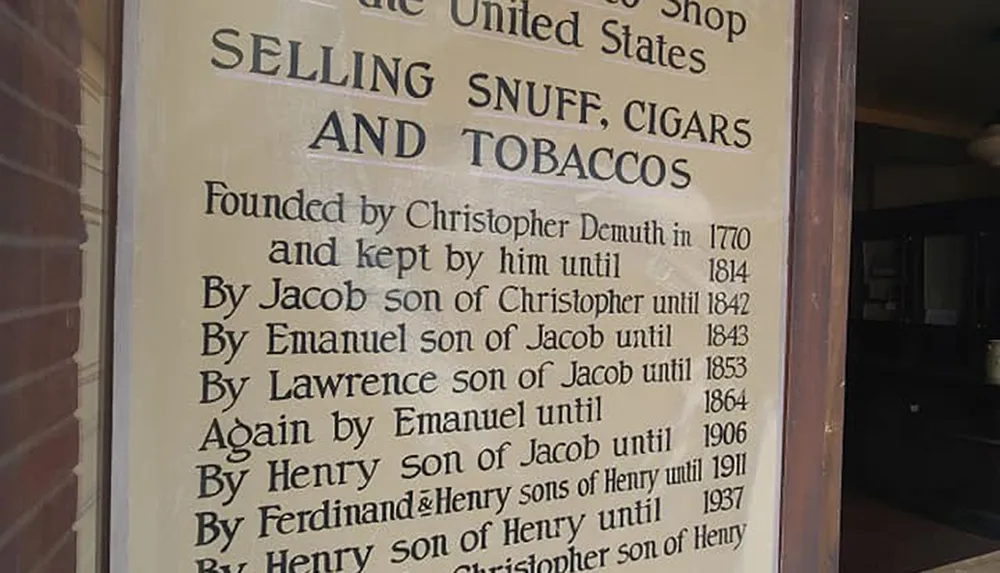 This image shows a plaque with historical information about a family-owned snuff cigars and tobaccos shop in the United States indicating it was founded by Christopher Demuth in 1770 and operated by successive generations of his family