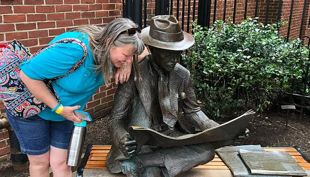 A person is leaning affectionately against a statue of a seated figure reading a book creating a whimsical and endearing scene