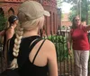 A group of people is listening to a woman who appears to be giving a tour or presentation outdoors