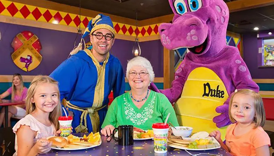 A family, including two children and an elderly woman, is enjoying a meal at a colorful restaurant with a person in a blue costume and a character mascot dressed in a purple dinosaur suit labeled Duke.