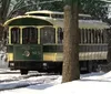 A cheerful woman in historical attire is engaging with passengers likely performing or narrating in a vintage train carriage