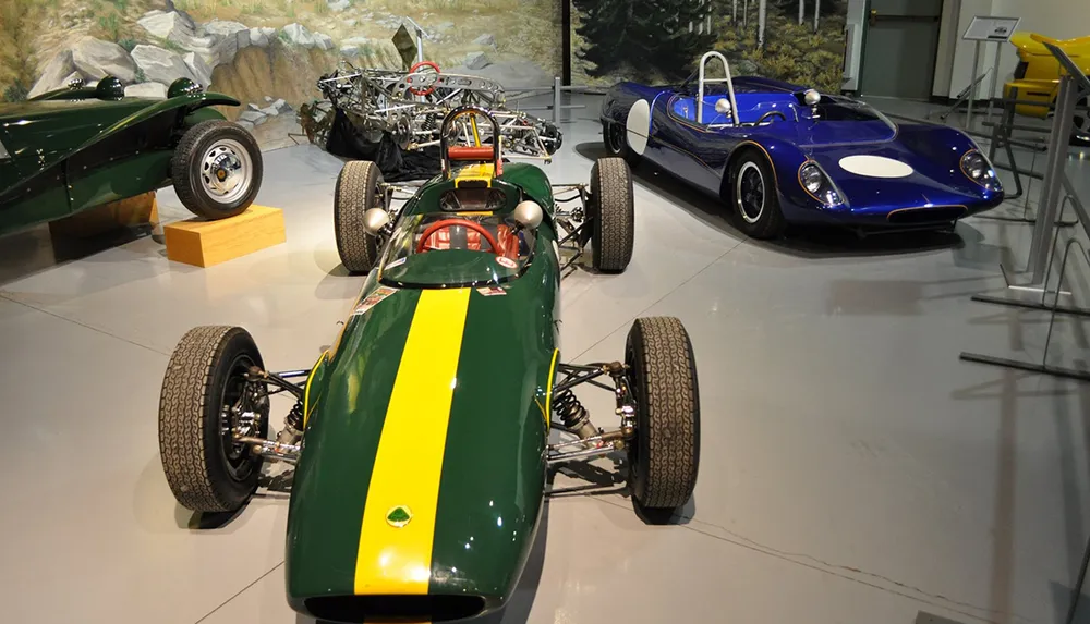The image shows a collection of classic racing cars on display in a museum setting highlighting the sleek designs and engineering of an earlier era of motorsport