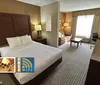 The image shows a hotel room with a comfortable bed seating area desk and natural light featuring amenities like free Wi-Fi an indoor pool and complimentary breakfast