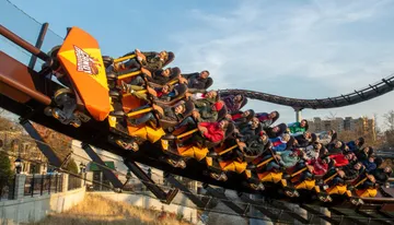 Thrill-seekers experience a sharp turn on a roller coaster with expressions of excitement and enjoyment.