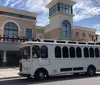 A trolley-style bus is parked in front of a building with a sign that reads GRAND 14