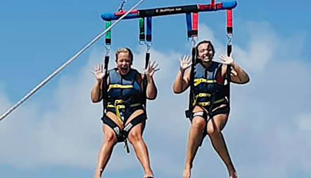 Two people are enjoying a parasailing adventure in clear skies