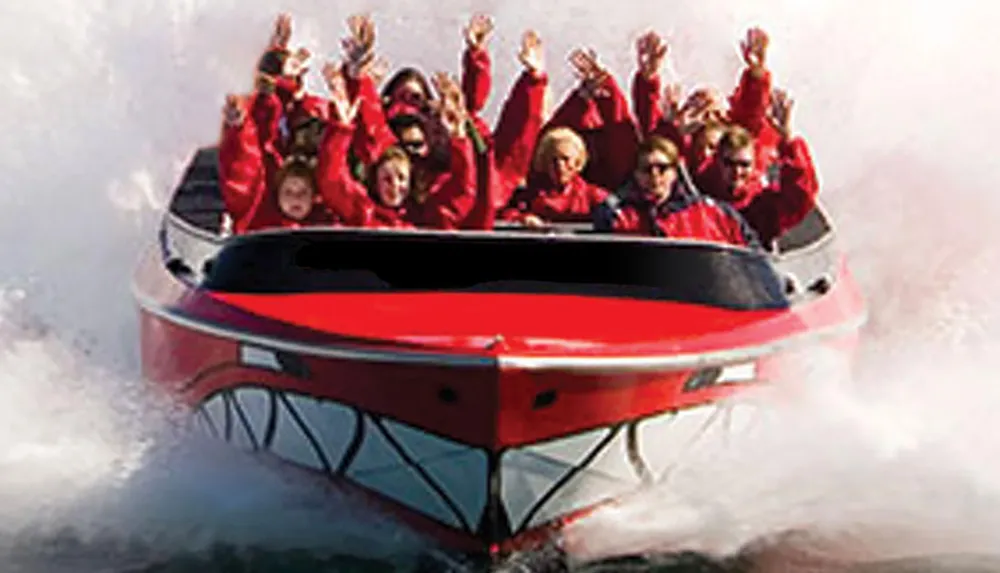 The image shows a group of excited passengers wearing red life jackets raising their arms with joy while riding a high-speed boat creating large sprays of water
