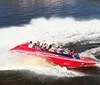A group of people wearing life vests are enjoying a thrilling boat ride as water splashes around them