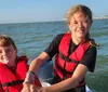 A man is smiling and holding up a large fish he caught while on a boat in the sea