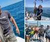 A man and a woman are smiling and posing with two freshly caught fish on a boat with the ocean in the background