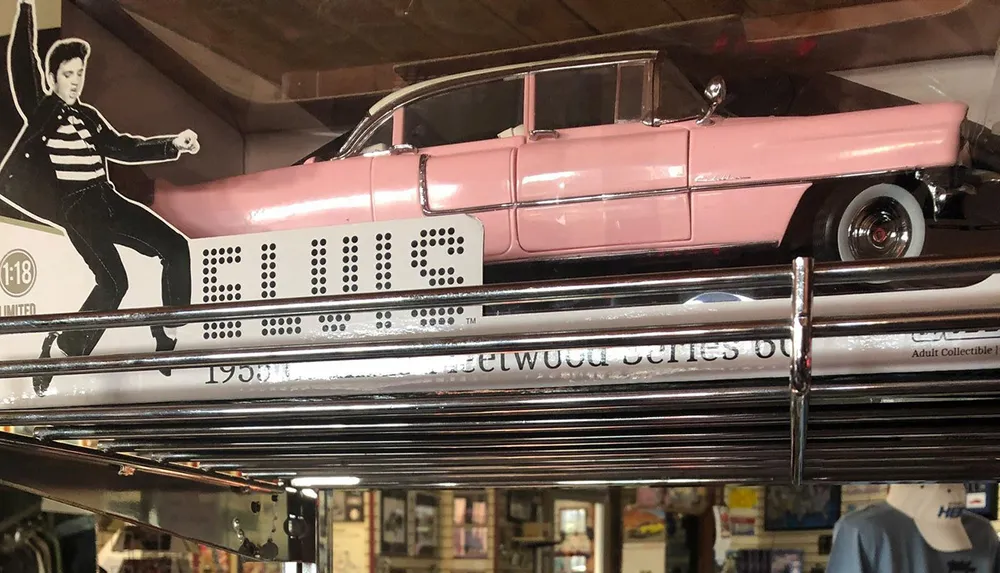 The image shows a model of a pink 1955 Cadillac Fleetwood alongside a cutout of a person in a dynamic pose with the name ELVIS displayed prominently