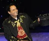 A person in a colorful ornate jacket poses dramatically next to a disco ball with a vibrant abstract background