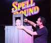 A magician performs a trick involving a woman in a box with the word SPELLBOUND in colorful letters behind them