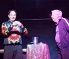 A magician performs a trick involving a woman in a box with the word SPELLBOUND in colorful letters behind them