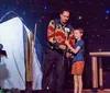 A magician performs a trick involving a woman in a box with the word SPELLBOUND in colorful letters behind them