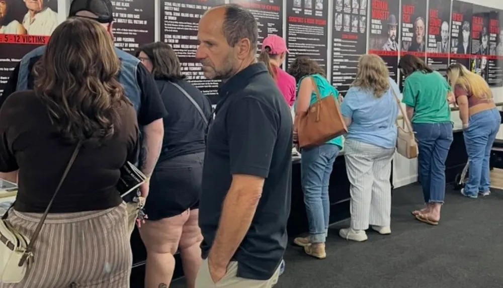 A group of people are viewing exhibition panels in a confined space