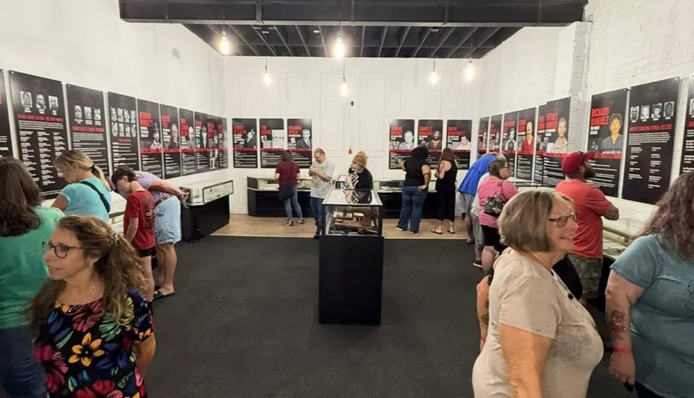 People are viewing an exhibition with informational panels and display cases in a gallery setting