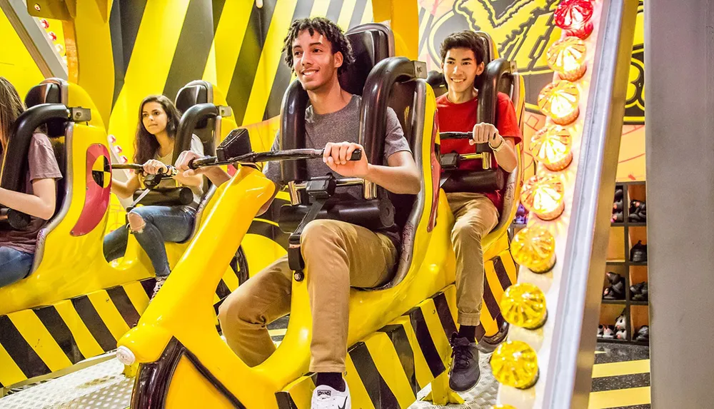 People are seated on a vibrant yellow and black amusement park ride appearing excited and enjoying the experience