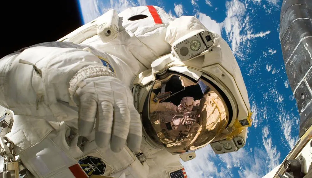 An astronaut in a space suit is captured in a selfie outside a spacecraft with Earth visible in the background