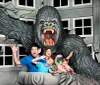 A family poses for a playful photo with a large 3D King Kong exhibit as though they are being attacked