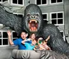 A family poses for a playful photo with a large 3D King Kong exhibit as though they are being attacked