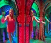 A woman and a man are navigating through a colorful mirror maze creating multiple reflections