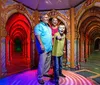 A woman and a man are navigating through a colorful mirror maze creating multiple reflections