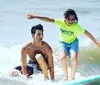 Two people are wearing wetsuits and lying on surfboards paddling in the ocean