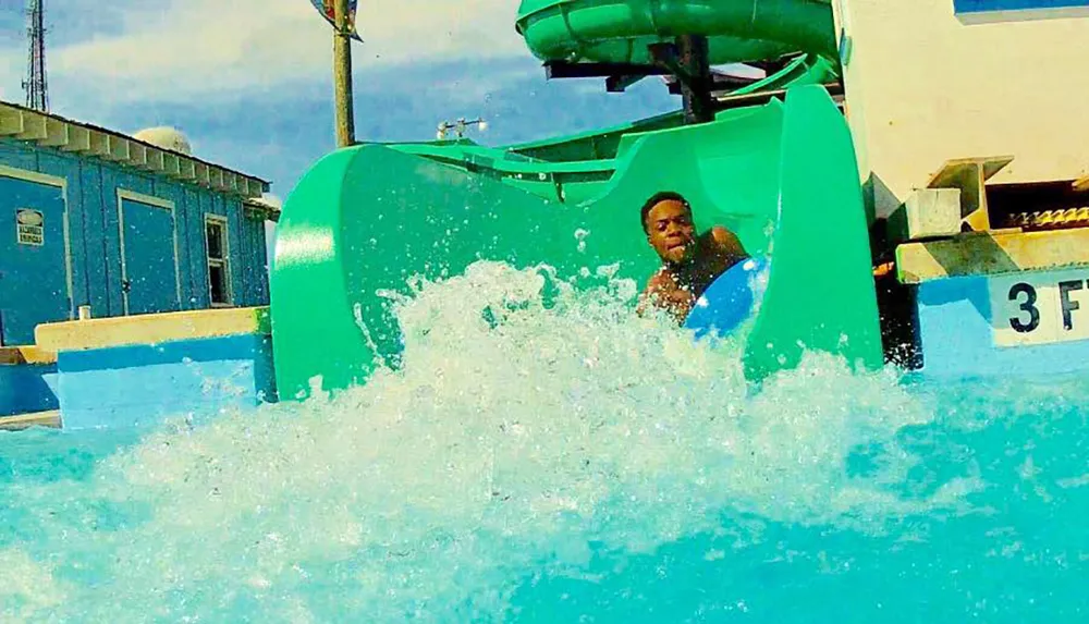 A person is seen emerging with a splash from a water slide at a water park