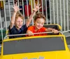 People are enjoying a ride in go-karts on a sunny day at a track