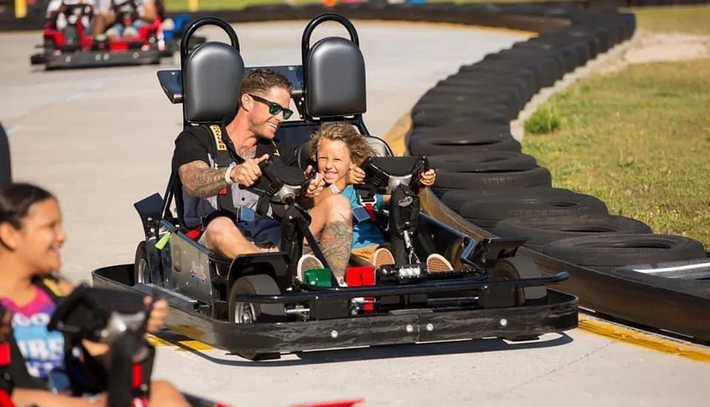 An adult and a child enjoy a thrilling go-kart ride together sharing a light-hearted moment full of smiles