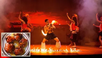 A group of performers engages in a traditional fire dance, with a central figure manipulating flames while others dance around him against a dramatically lit backdrop.