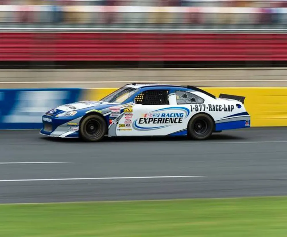 A race car is captured in motion on a speedway exhibiting motion blur which conveys its high speed