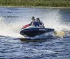 Two people are riding a jet ski with water splashing around them as they speed across a lake