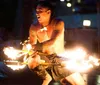 A performer with traditional tattoos is demonstrating a fire dance at night skillfully manipulating flaming objects