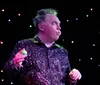 A performer enthusiastically entertains a group of children on stage under a starry light backdrop