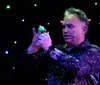 A performer enthusiastically entertains a group of children on stage under a starry light backdrop