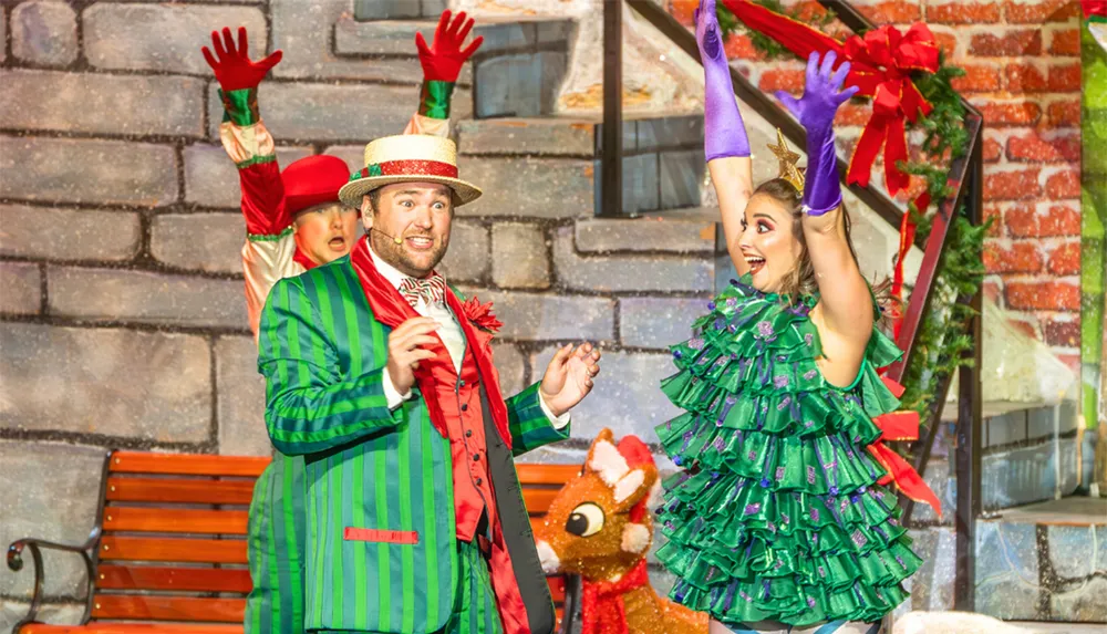 Two performers in festive costumes express excitement on a colorful holiday-themed stage
