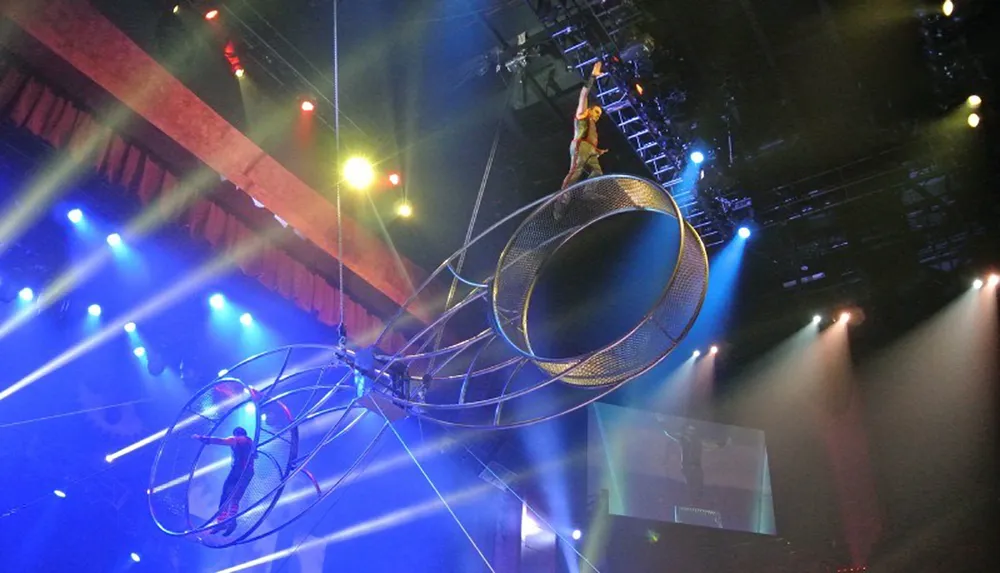 Performers execute a daring act on the Wheel of Death under a dramatic array of stage lights