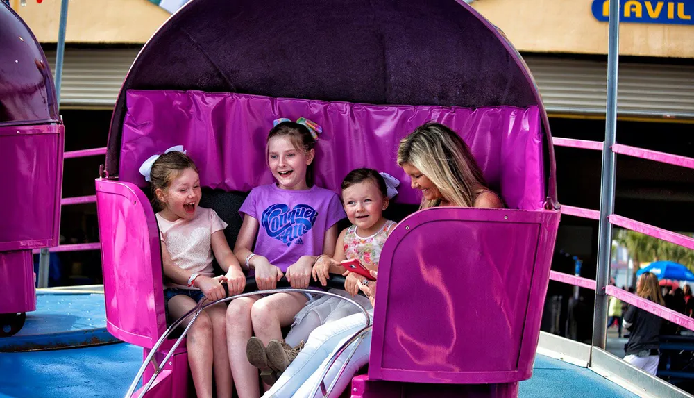 A group of joyous people likely a family are sharing a fun moment on a bright purple amusement park ride