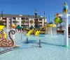 A colorful childrens water play area with slides and aquatic-themed sculptures at a hotel or resort under a clear blue sky