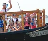 A group of people enjoy a boat ride on a miniature pirate ship flying a Jolly Roger flag