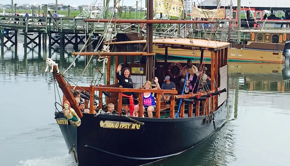 A group of passengers is enjoying a boat ride on a pirate-themed vessel called Sea Gypsy III in a calm marina environment