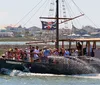 A group of people enjoy a boat ride on a miniature pirate ship flying a Jolly Roger flag